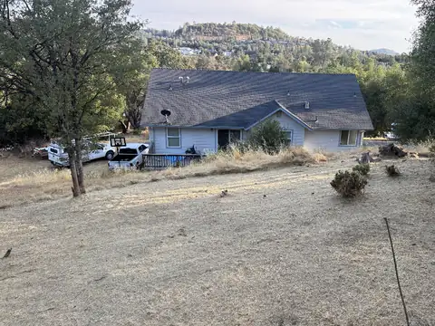 A single-story house on a hillside with the dry grass on the slope below it cut short
