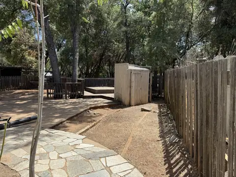 A strip of bare ground cleared along a wooden fence beside a flagstone path